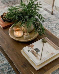 a wooden table topped with a book and a potted plant next to a candle