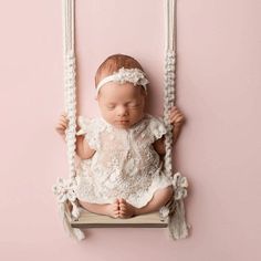 a baby is sitting on a swing with her hands in the air and eyes closed