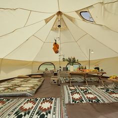 the inside of a large tent with several beds and rugs on top of it