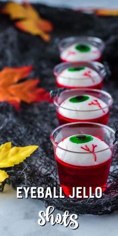 three cups filled with jello sitting on top of a table next to fall leaves