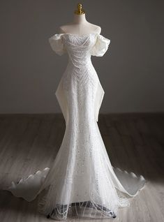 a white wedding dress on display in front of a mannequin headdress