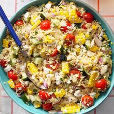 a blue bowl filled with rice, tomatoes and corn on top of a checkered table cloth