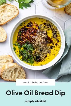 a bowl of olive oil bread dip on a white table with sliced bread and parsley