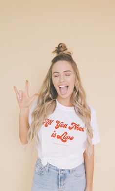 a woman with her hands in the air while wearing a t - shirt that says all you need is love