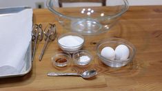 an assortment of kitchen utensils sitting on a wooden table next to a glass bowl