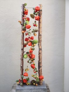 an artistic sculpture made out of branches and apples on display in a room with white walls