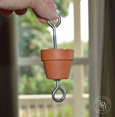 a hand holding a potted plant on a metal hook