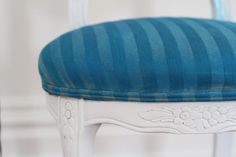 a white chair with a blue cushion on it's back and seat padding