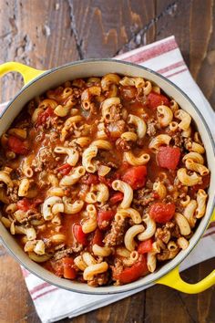 a pot filled with pasta and meat on top of a wooden table