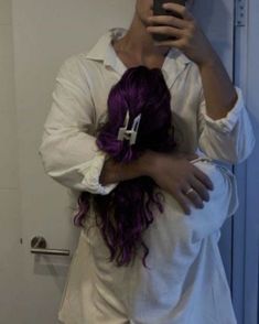 a woman with purple hair taking a selfie in front of a mirror while holding her cell phone