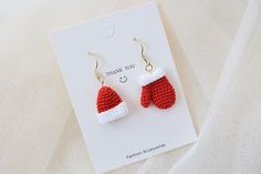 a pair of red and white knitted christmas mittens earrings with thank you written on them