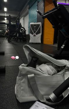 an empty gym bag sitting on the floor next to a weight scale and exercise equipment