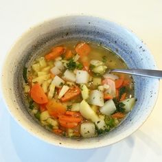 a bowl of soup with carrots, celery and other veggies