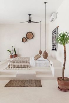 a bed sitting in the middle of a living room next to a potted plant