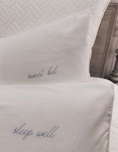 two white pillows with blue writing on them