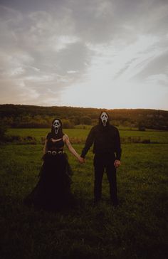 two people wearing masks holding hands in a field