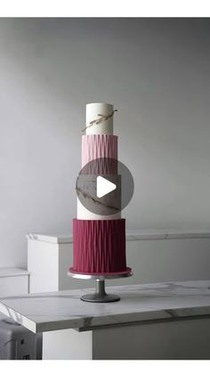 a three tiered cake with pink and white icing on it's side