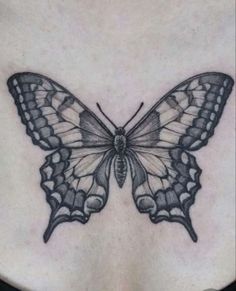 a woman's chest with a butterfly tattoo on the top and bottom part of her stomach