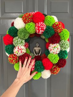 a person is holding up a christmas wreath with pom - poms on it