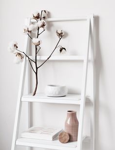 a white ladder shelf with flowers and vases on it