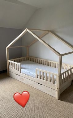 a wooden bed with a red heart on the floor next to it in a room