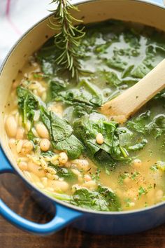 spinach and chickpeas soup in a blue pot with a wooden spoon