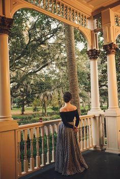 a woman standing on a porch next to a palm tree in front of a gazebo