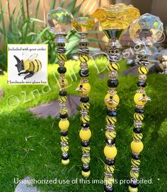 three yellow and black glass candlesticks in the grass with a bee on them