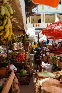 an open air market with lots of fruit and vegetables on the tables under umbrellas