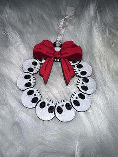 a red and white wreath with black polka dots hanging on a fur surface, decorated with a red bow