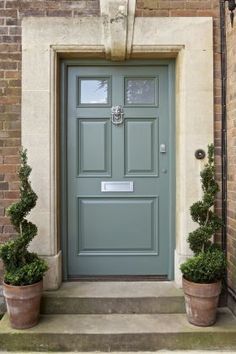 a green front door with two potted plants