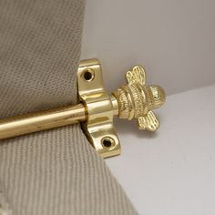 a close up view of a gold door handle on a beige fabric curtain with a white background