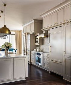 a large kitchen with white cabinets and silver appliances in the center, along with blue chairs