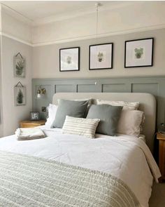 a white bed sitting in a bedroom next to two pictures on the wall above it