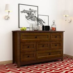 a wooden dresser sitting on top of a red and white floor next to a painting