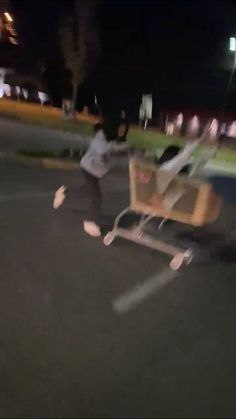 a man pushing a shopping cart in the parking lot at night with motion blurry