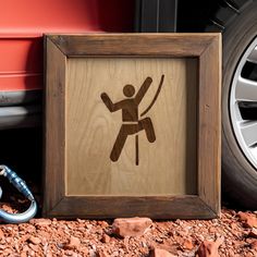 a wooden sign with a man holding a bow in front of a red car on the ground