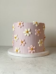 a pink cake with white and yellow flowers on it