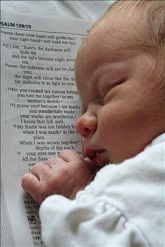 a baby laying on top of an open book with its head resting on it's hands