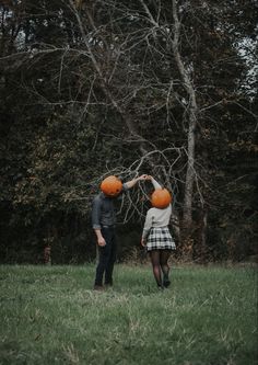 two people in a field with orange balls on their heads