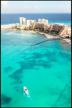 an aerial view of the ocean with a boat in the foreground and hotels in the background