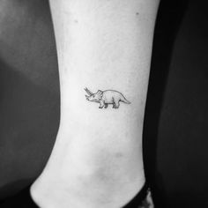 a small rhinoceros tattoo on the ankle that is black and white with an arrow