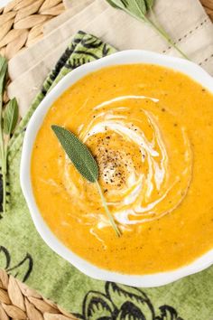 a white bowl filled with carrot soup on top of a green napkin