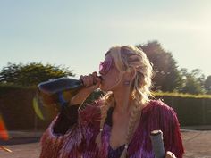 a woman drinking from a bottle while walking down the street