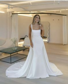 a woman in a white wedding dress posing for the camera with her hand on her hip