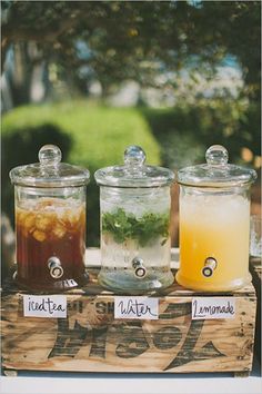 three jars filled with drinks sitting on top of a wooden box next to each other