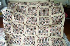 a quilted blanket sitting on top of a wooden floor next to a window sill