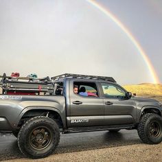 a truck with a rainbow in the background and a person sitting in the back seat