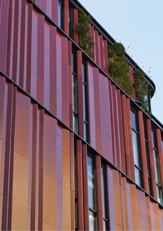 the side of a building with red and orange stripes on it's sides, as seen from below