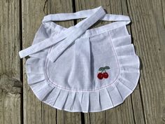 a white bag with cherries on it sitting on top of a wooden table next to a piece of wood